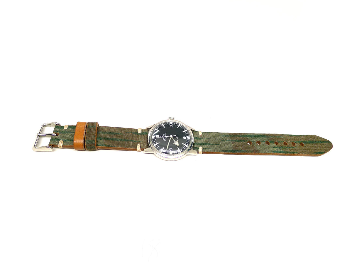 Amminmol watch strap in olive green and brown with streaked markings and an orange keeper, shown fitted to a watch.