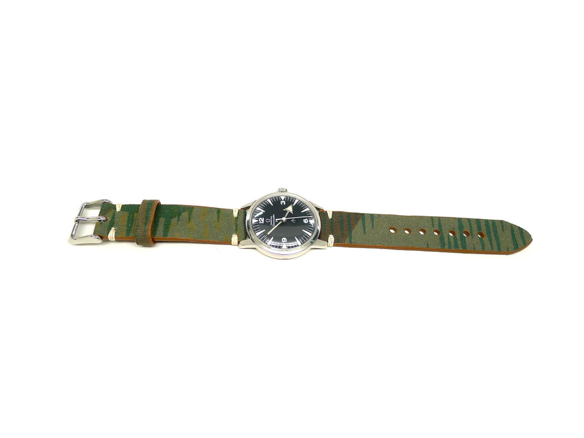 Eagar watch strap in green and brown with streaked markings and cream accent stitches, shown fitted to a watch.