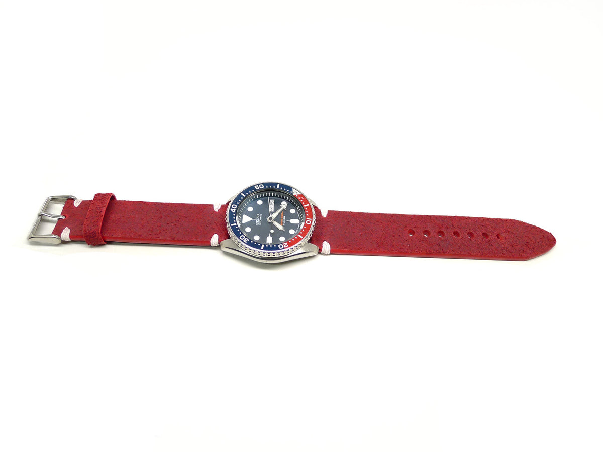 Flebboh watch strap in red with a textured surface and white accent stitches, shown fitted to a watch.