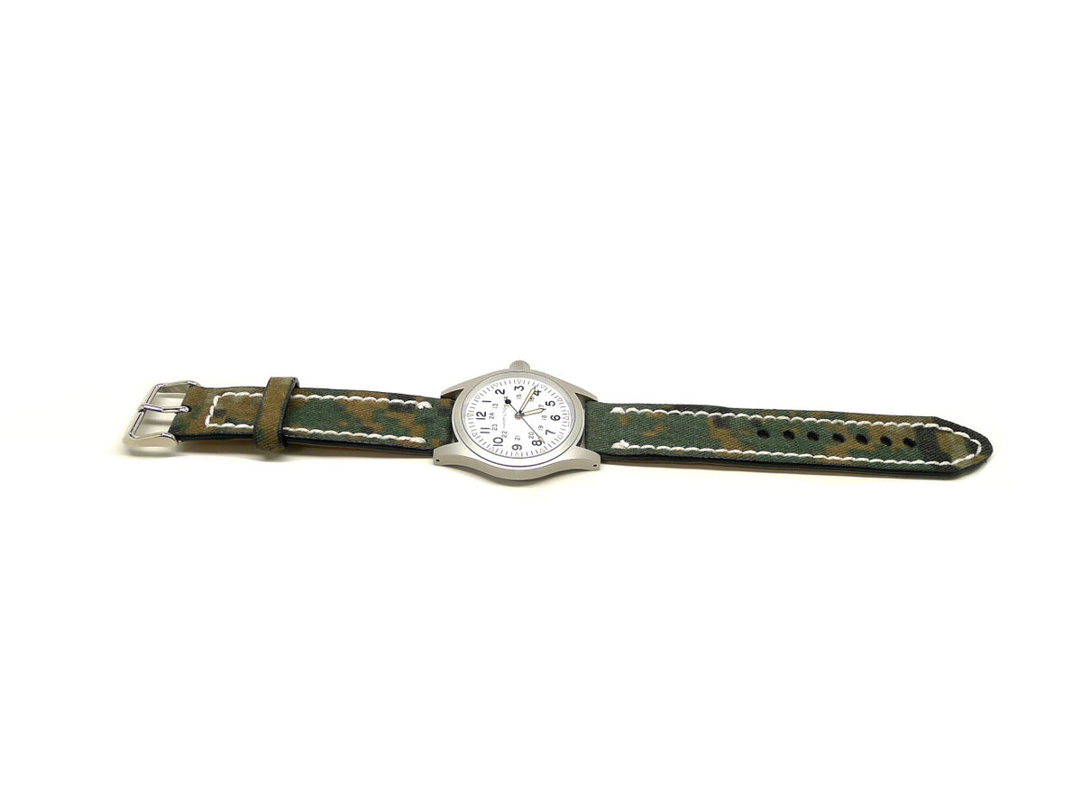 Heint watch strap in green and brown with a camouflage pattern and cream edge stitching, shown fitted to a watch.