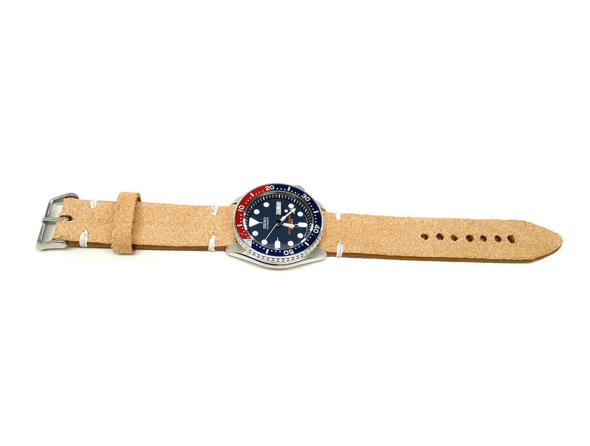 Nanda Devi watch strap in light tan with a textured surface and cream accent stitches, shown fitted to a watch.
