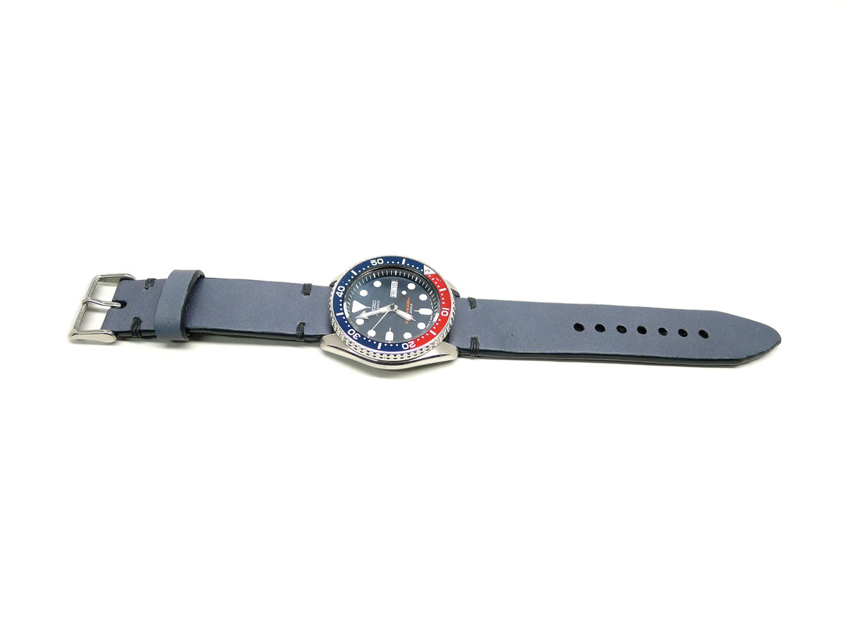 Sleutheo watch strap in blue gray with dark accent stitches, shown fitted to a watch.