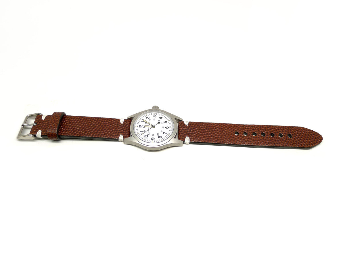 Whelsho watch strap in brown with a textured surface and white accent stitches, shown fitted to a watch.