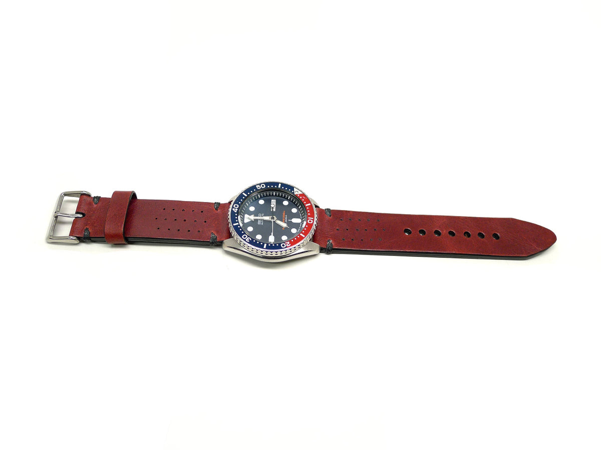 Woddio watch strap in dark red with small perforations and dark accent stitches, shown fitted to a watch.