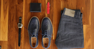 Leather dress shoes and accessories laid out on a wooden floor