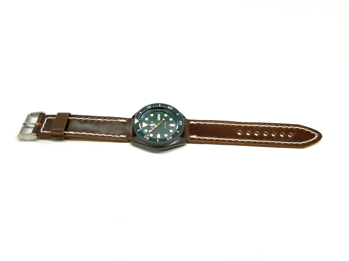 Demmili watch strap in dark brown with cream edge stitching, shown fitted to a watch.