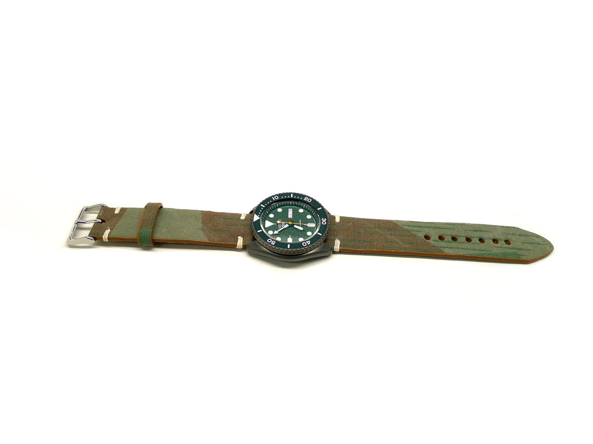 Montgomery watch strap in green and brown with broad diagonal markings and cream accent stitches, shown fitted to a watch.