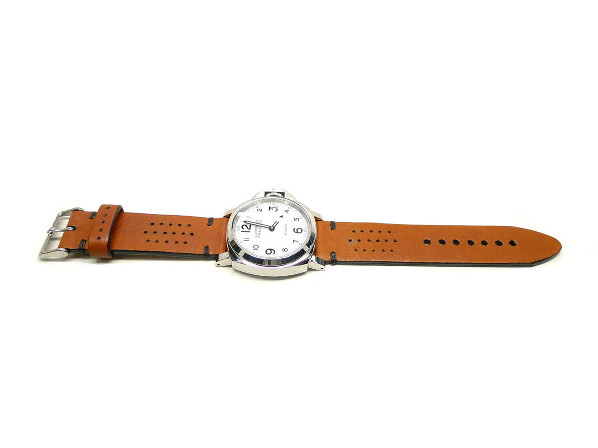 Pluncha watch strap in orange brown with small perforations and dark accent stitches, shown fitted to a watch.