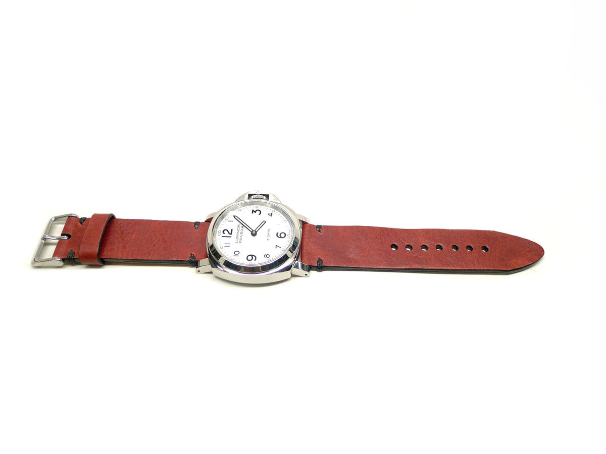Vlanza watch strap in red with dark accent stitches, shown fitted to a watch.