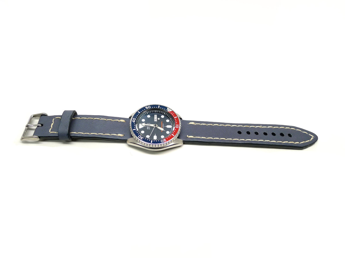 Vlossom watch strap in blue gray with cream edge stitching, shown fitted to a watch.