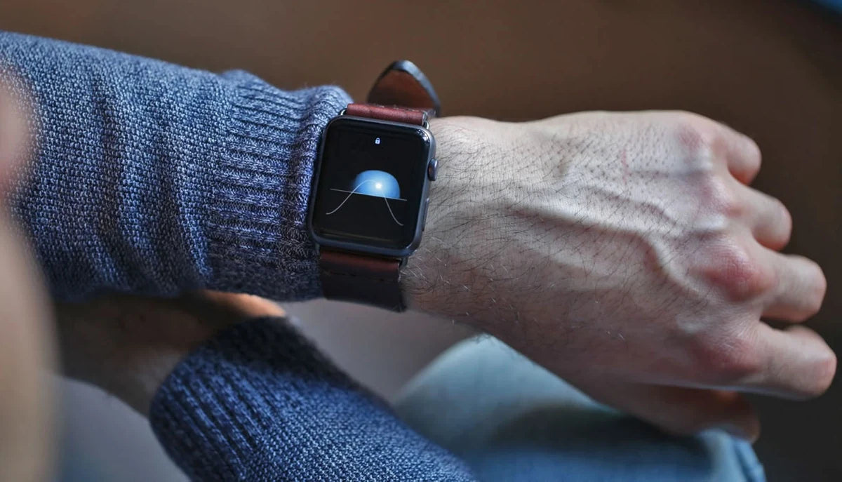 Apple Watch with a leather strap beside a blue knit sleeve