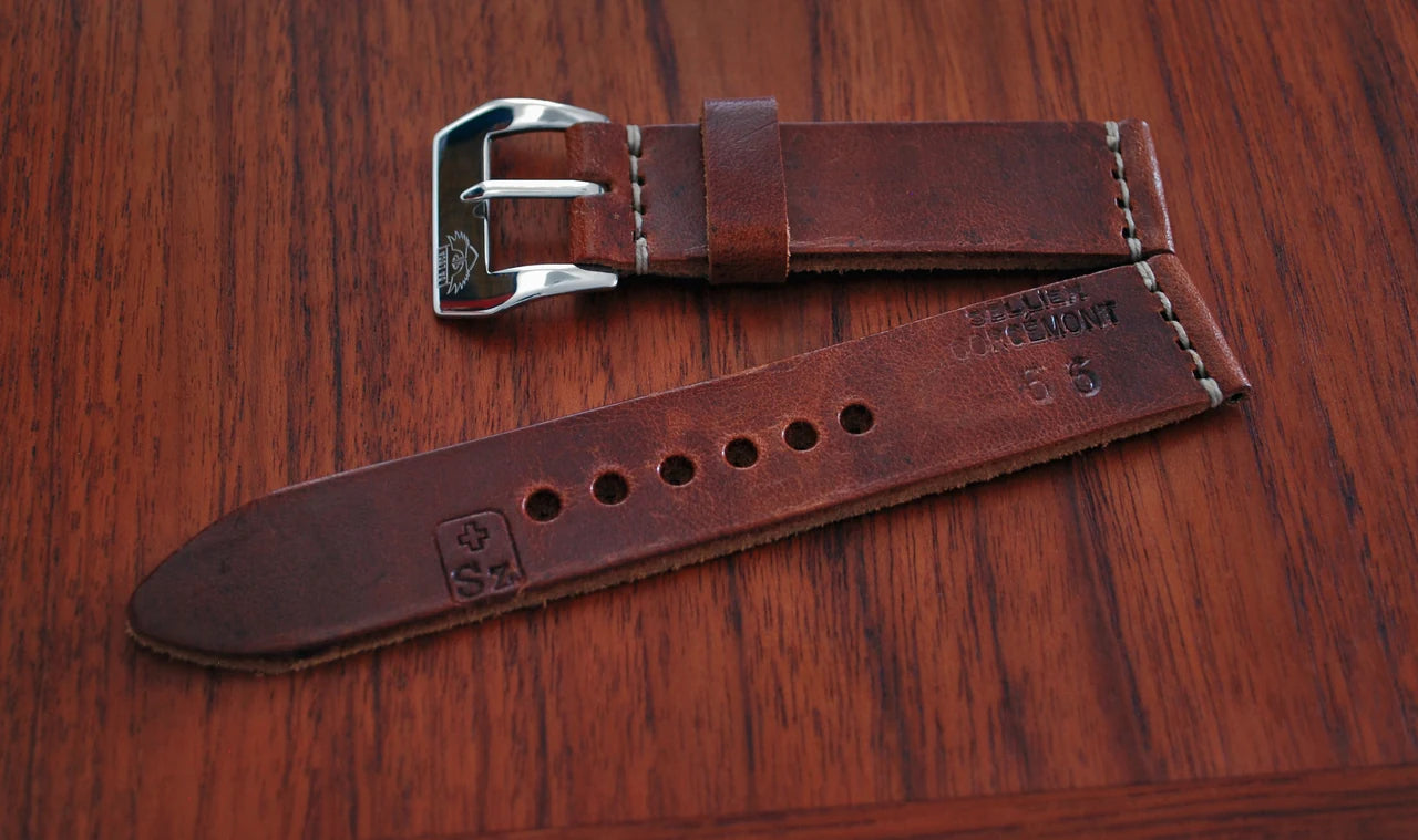 Swiss ammo leather watch strap with buckle and stamped markings on wood