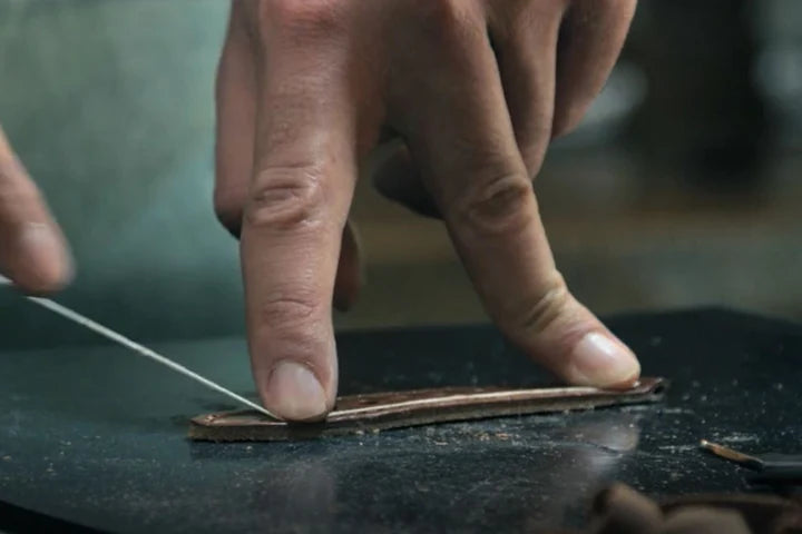 Hand stitching a leather watch strap with white thread